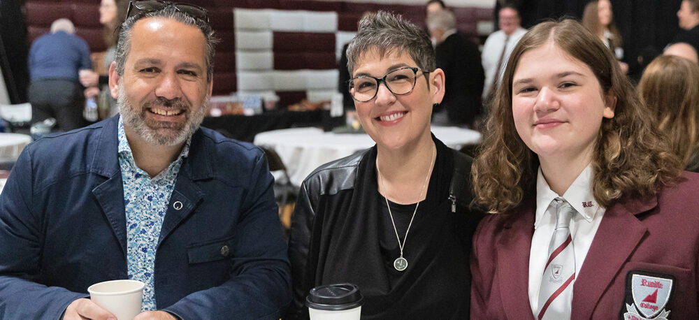 Rundle Academy | A Rundle Academy family smiles in the gymnasium during the Moves Mountains Breakfast | private school calgary