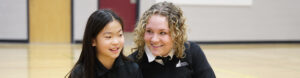 Rundle College | grade 12 and grade 4 student buddies smile in the gymnasium | private school calgary