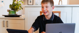 A Rundle Studio student sits at his laptop at the dining room at home.